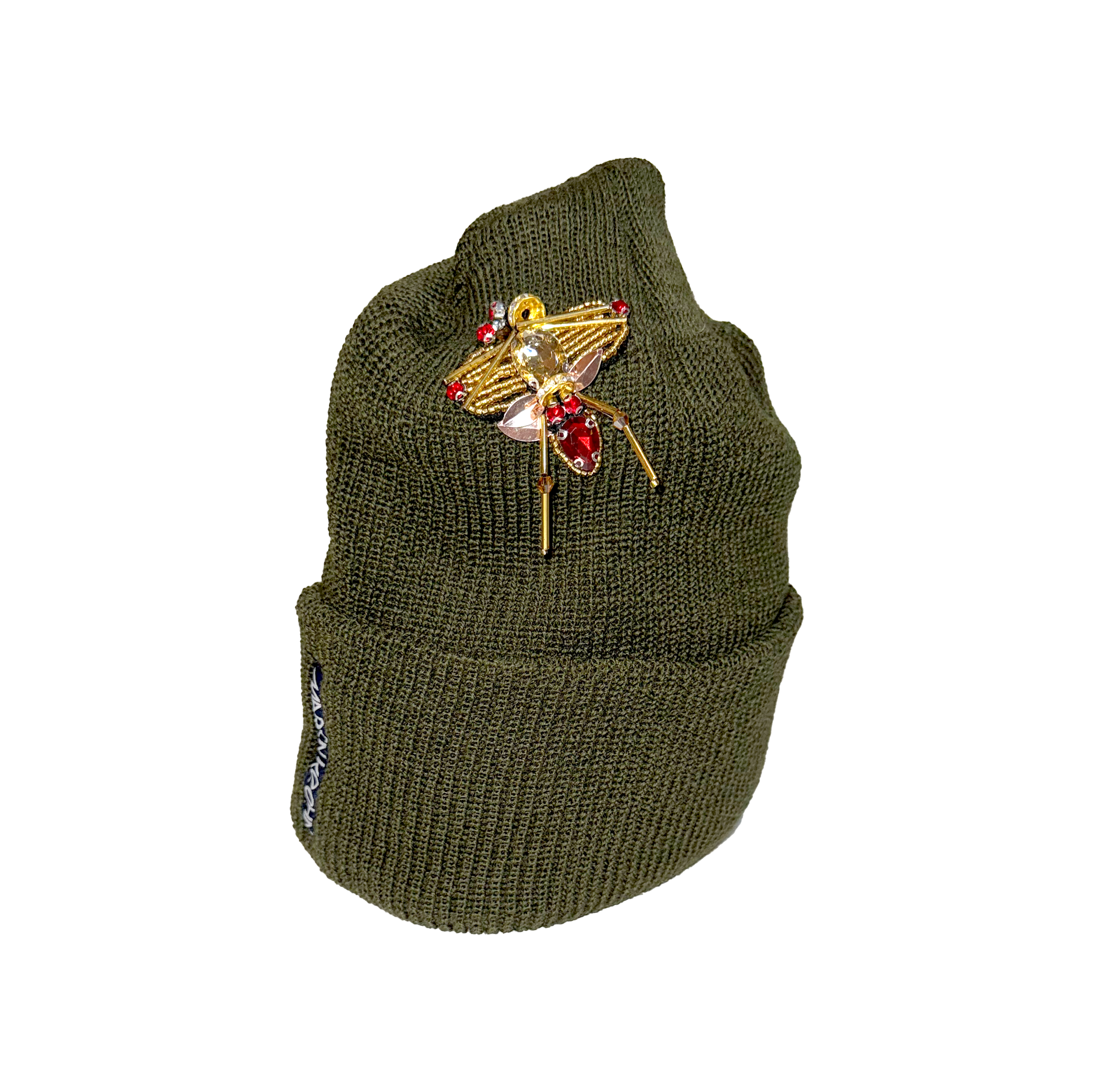 Green knit beanie with decorative brooch on a white background