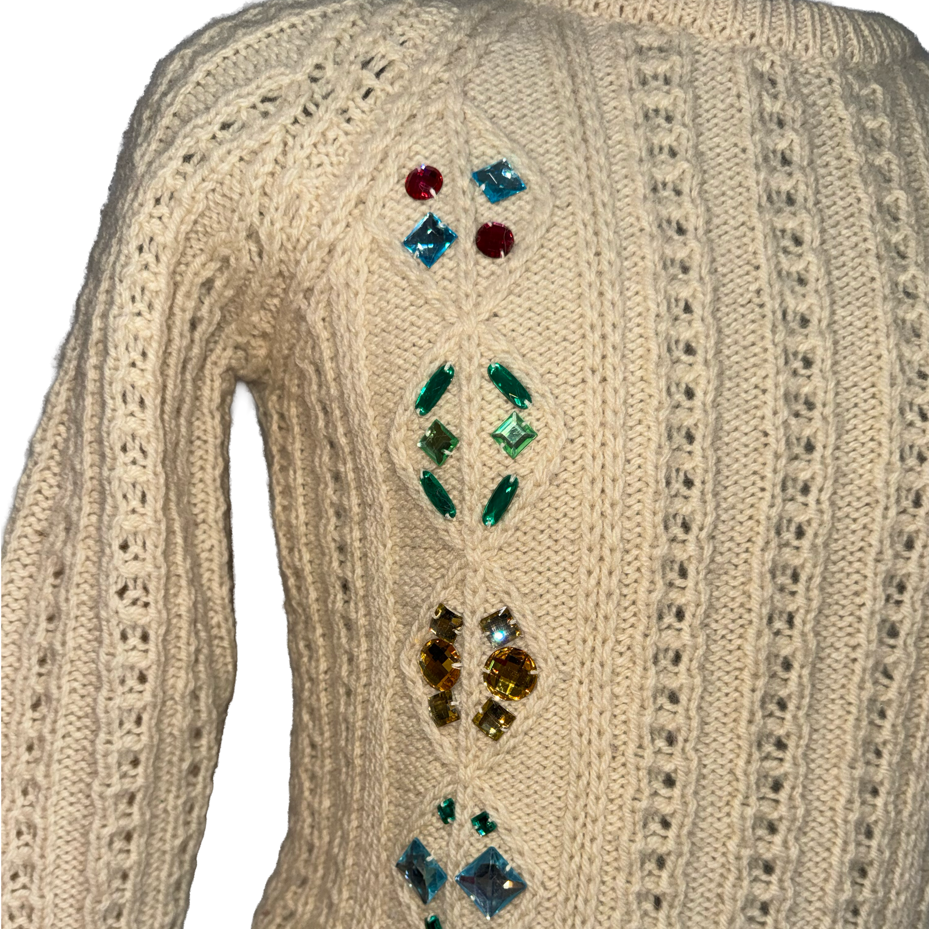 Close-up of the back of a cream-colored cable-knit sweater decorated with colorful rhinestone embellishments arranged vertically.