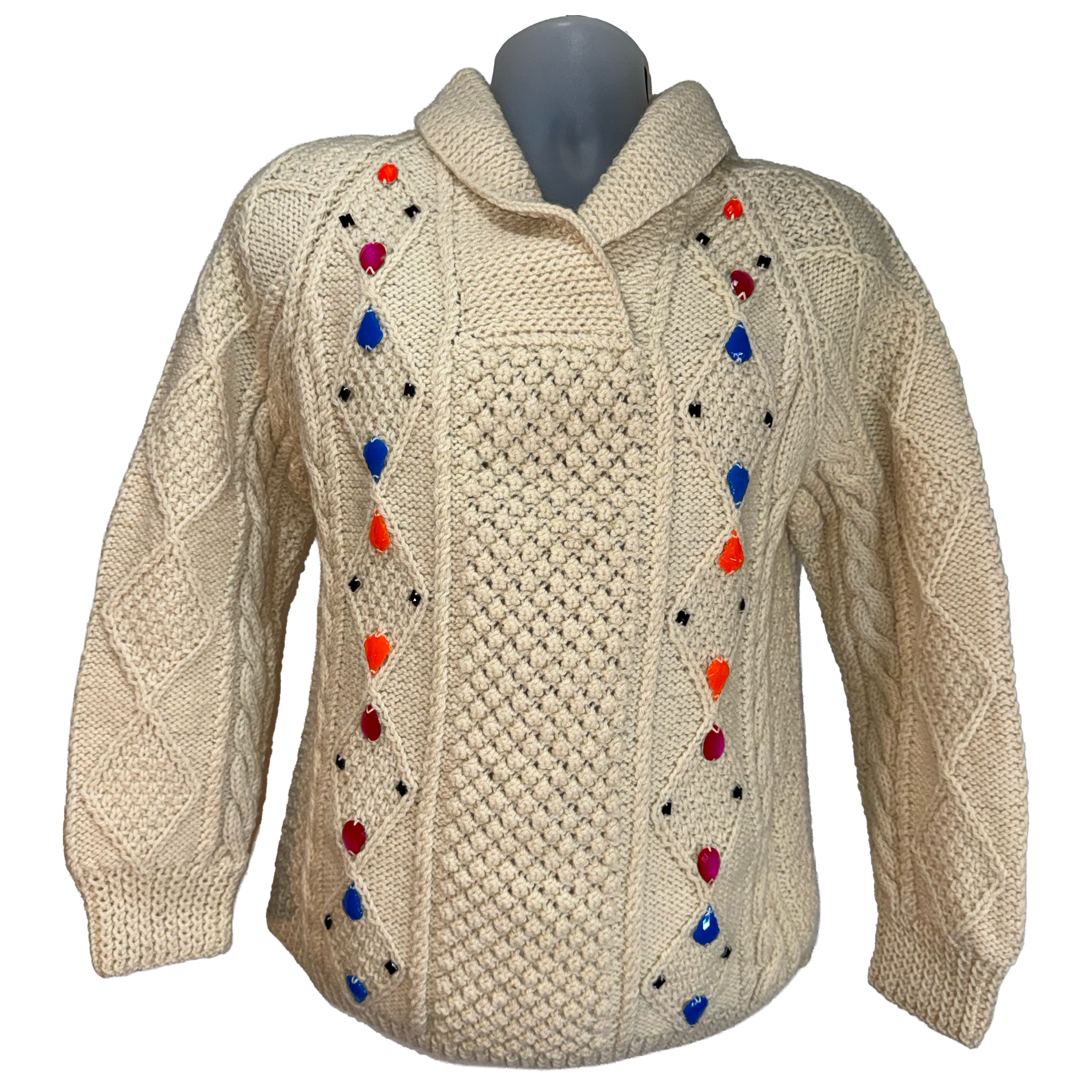 Cream cable-knit sweater with colorful teardrop-shaped knit embellishments in red, blue, orange, and black, displayed on a gray mannequin torso against a white background.